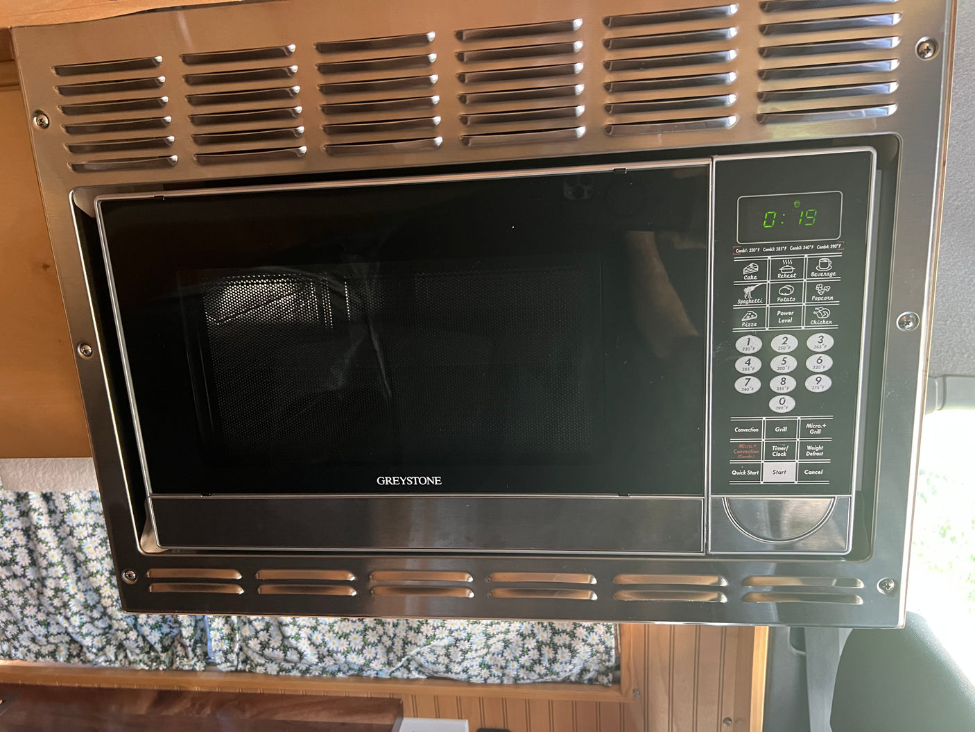 Stainless steel Greystone microwave with a digital display and control panel, ideal for an RV rental or camper kitchen.