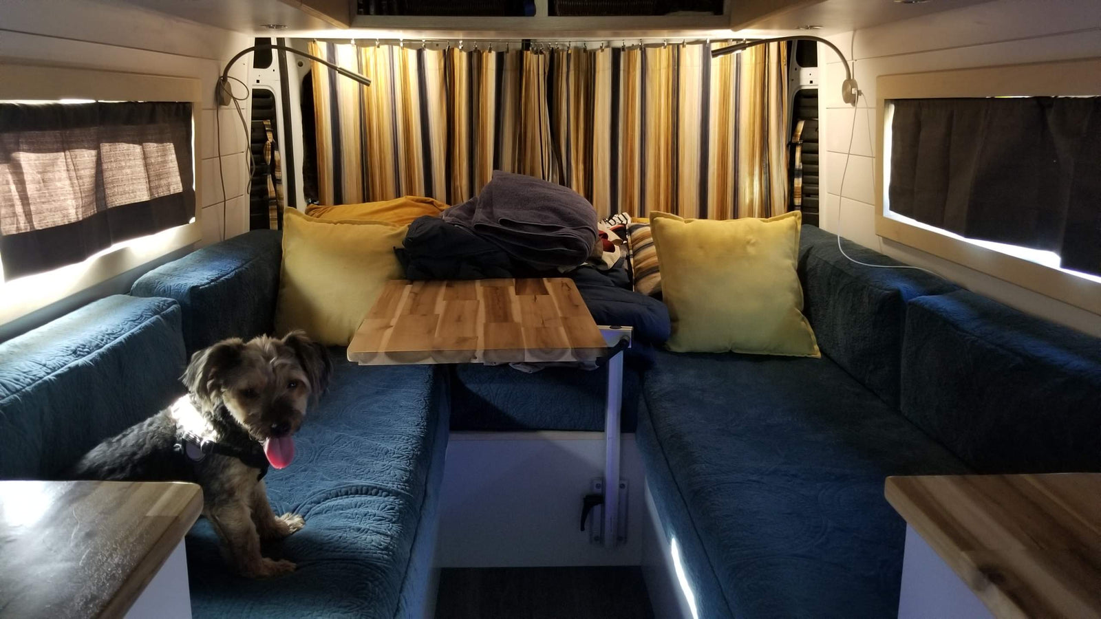 looking towards the driver's cab.|RV rental: customized camper van interior with a light wood folding table