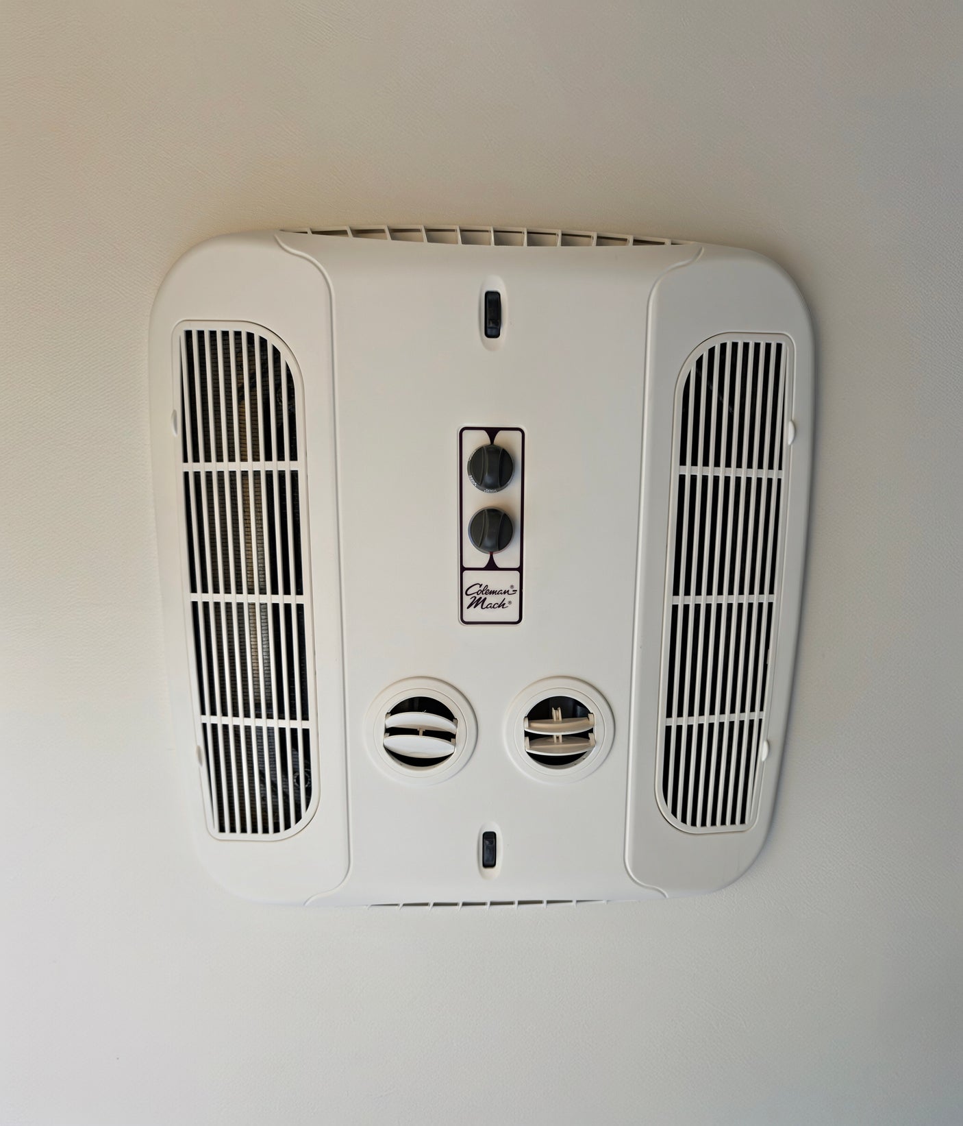 Stay cool in your RV rental! Ceiling-mounted Coleman Mach climate control unit with fan/temp knobs, vents & light switch.