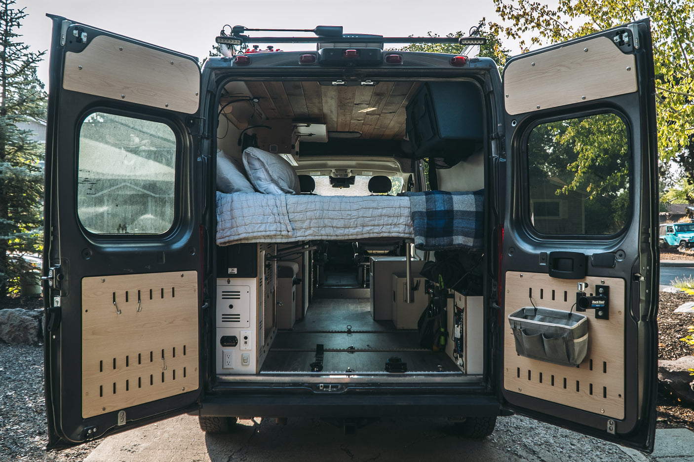 Rear view of a customized camper van interior, perfect for RV rental adventures. Features a cozy bed and smart storage.