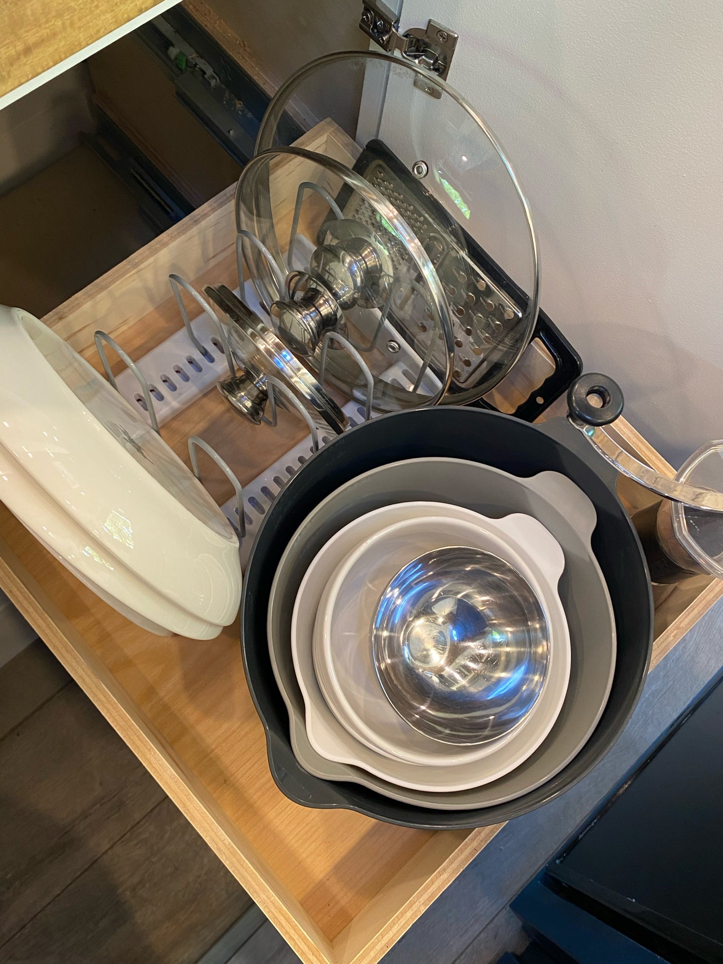RV rental kitchen drawer showing efficient storage: organized pot lids, grater, and nesting mixing bowls for cooking.
