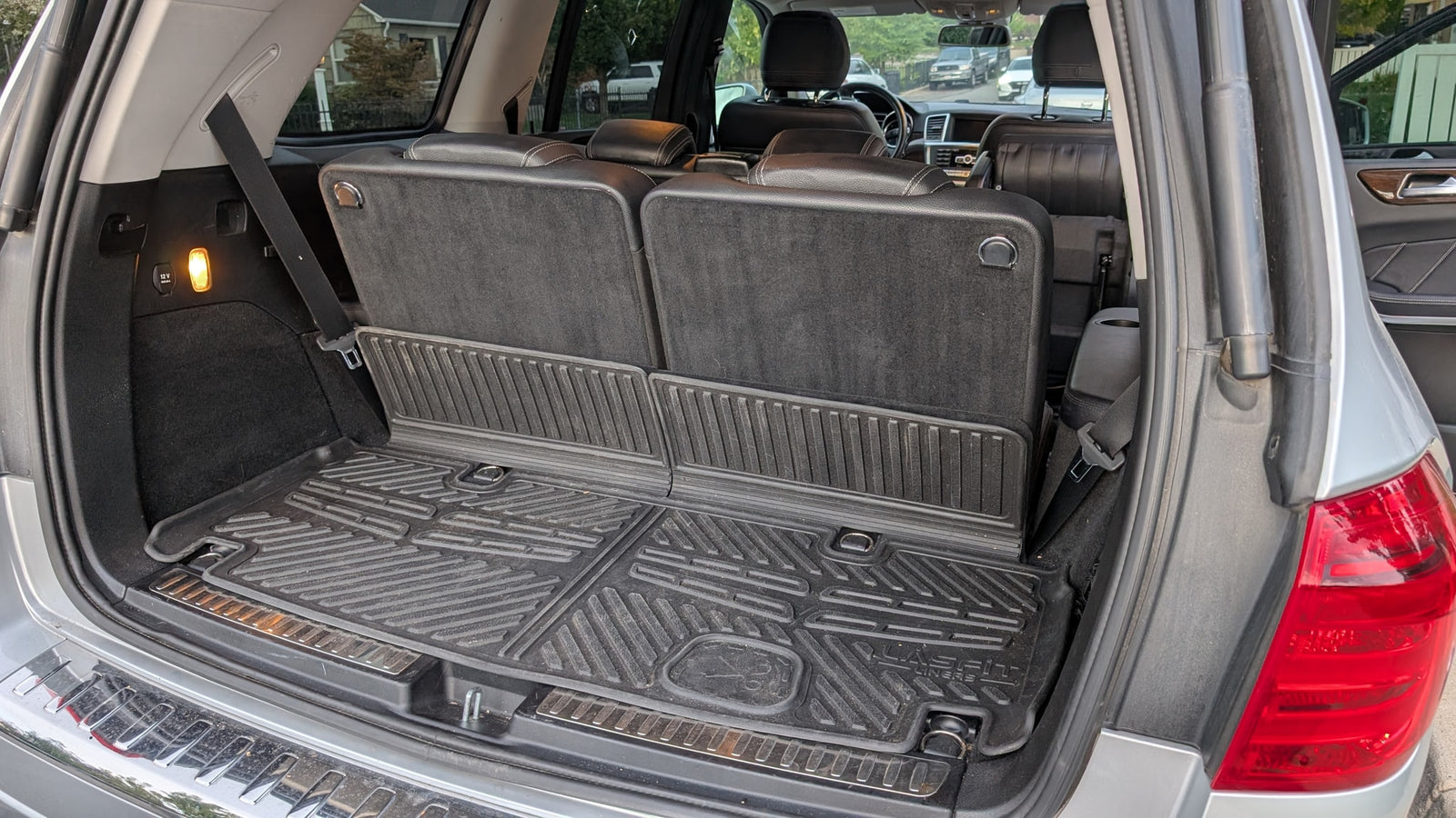 Spacious SUV cargo area with folded third-row seats, rubber mats, and a 12V outlet, ready for any rv rental trip.