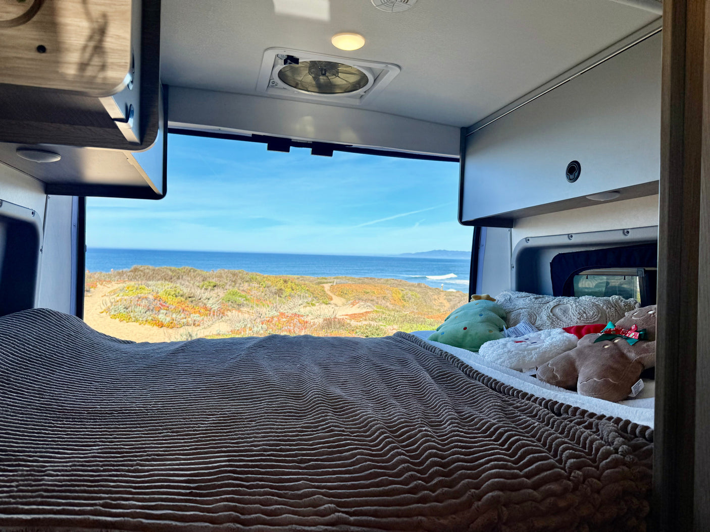 Enjoy an ocean view from your cozy RV rental bed, complete with soft blankets and fun plush toys. Ideal for a coastal retreat.