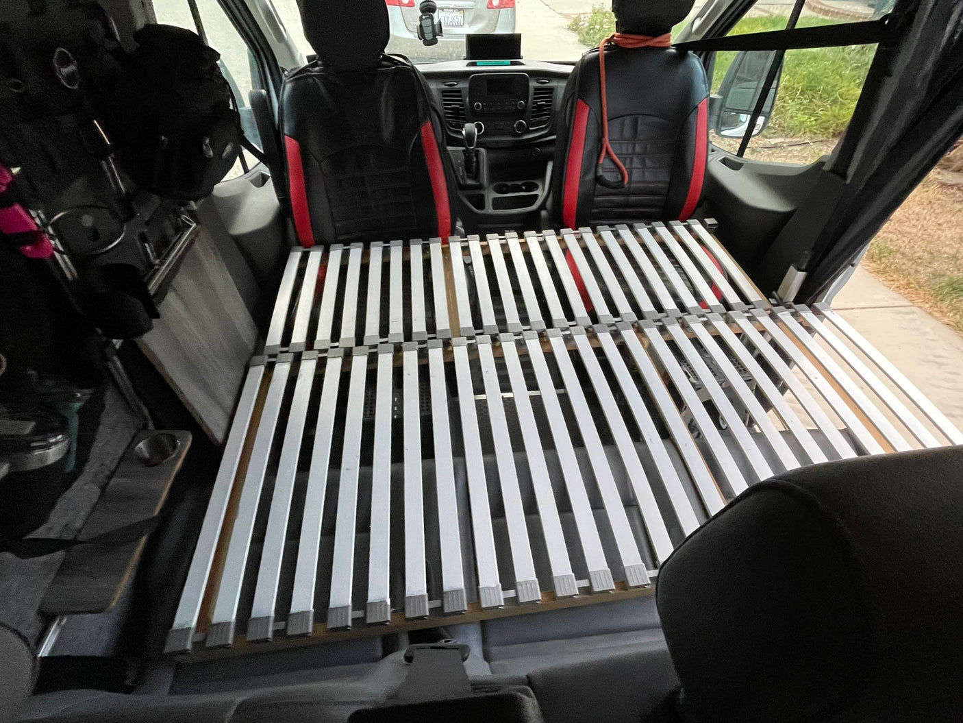 Inside an RV rental van featuring front seats and a convertible slat bed base, ideal for camping and road trips.