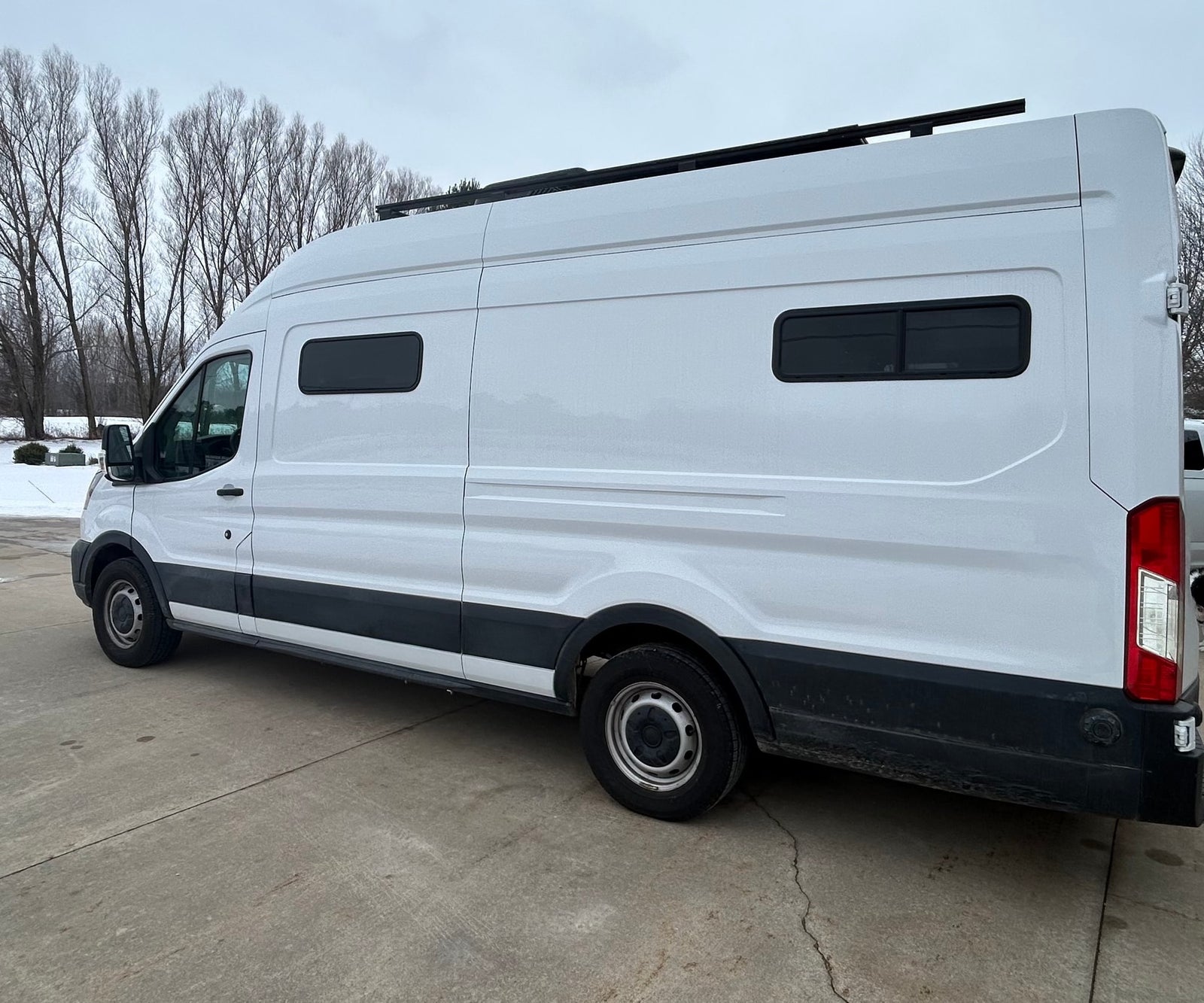 White camper van with a roof rack and custom windows, perfect for an RV rental adventure.
