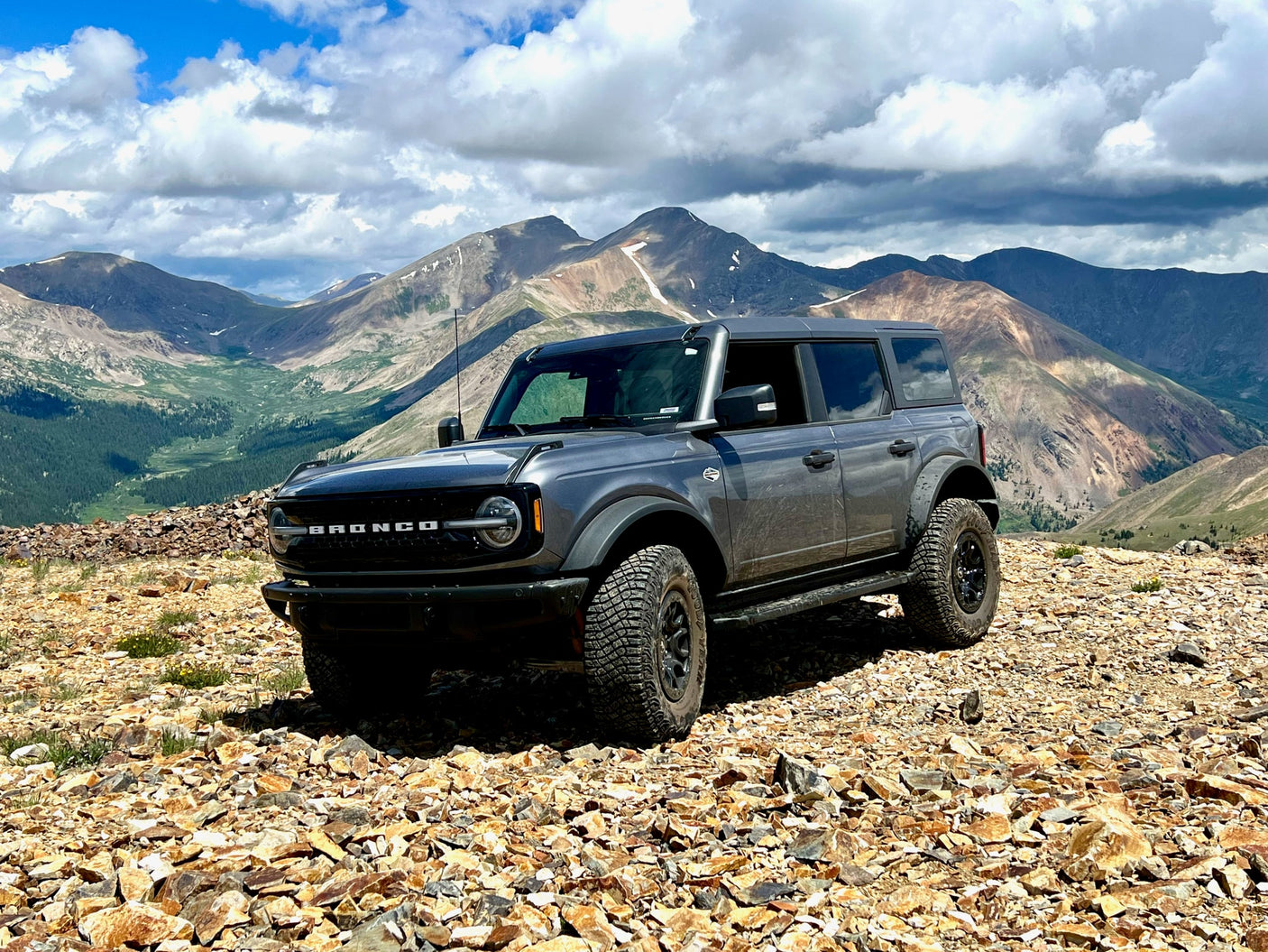 A gray Ford Bronco on a rocky mountain peak under cloudy skies. Your perfect companion for an off-road RV rental adventure.