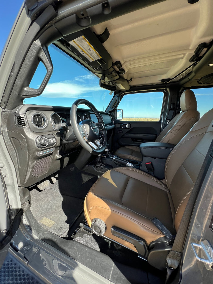 Open-air Jeep interior with rich brown leather seats and steering wheel, great for a scenic drive or an RV rental trip.
