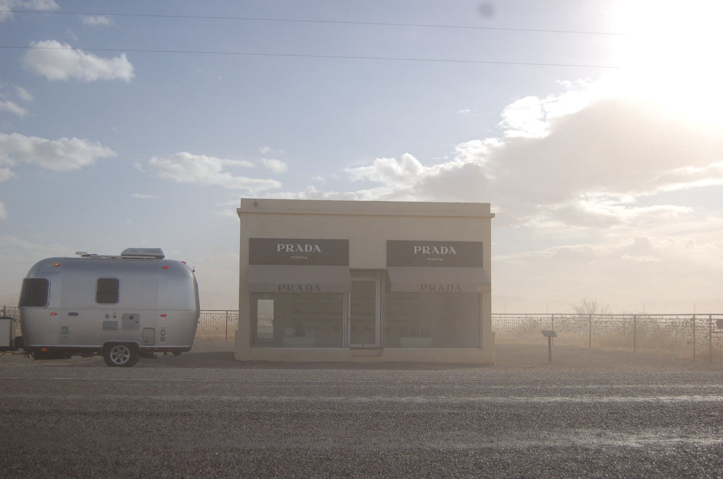 An RV rental, a silver Airstream, parked next to the famous Prada Marfa art installation in the Texas desert.