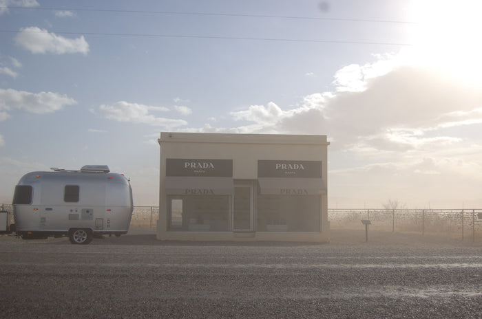 An RV rental, a silver Airstream, parked next to the famous Prada Marfa art installation in the Texas desert.