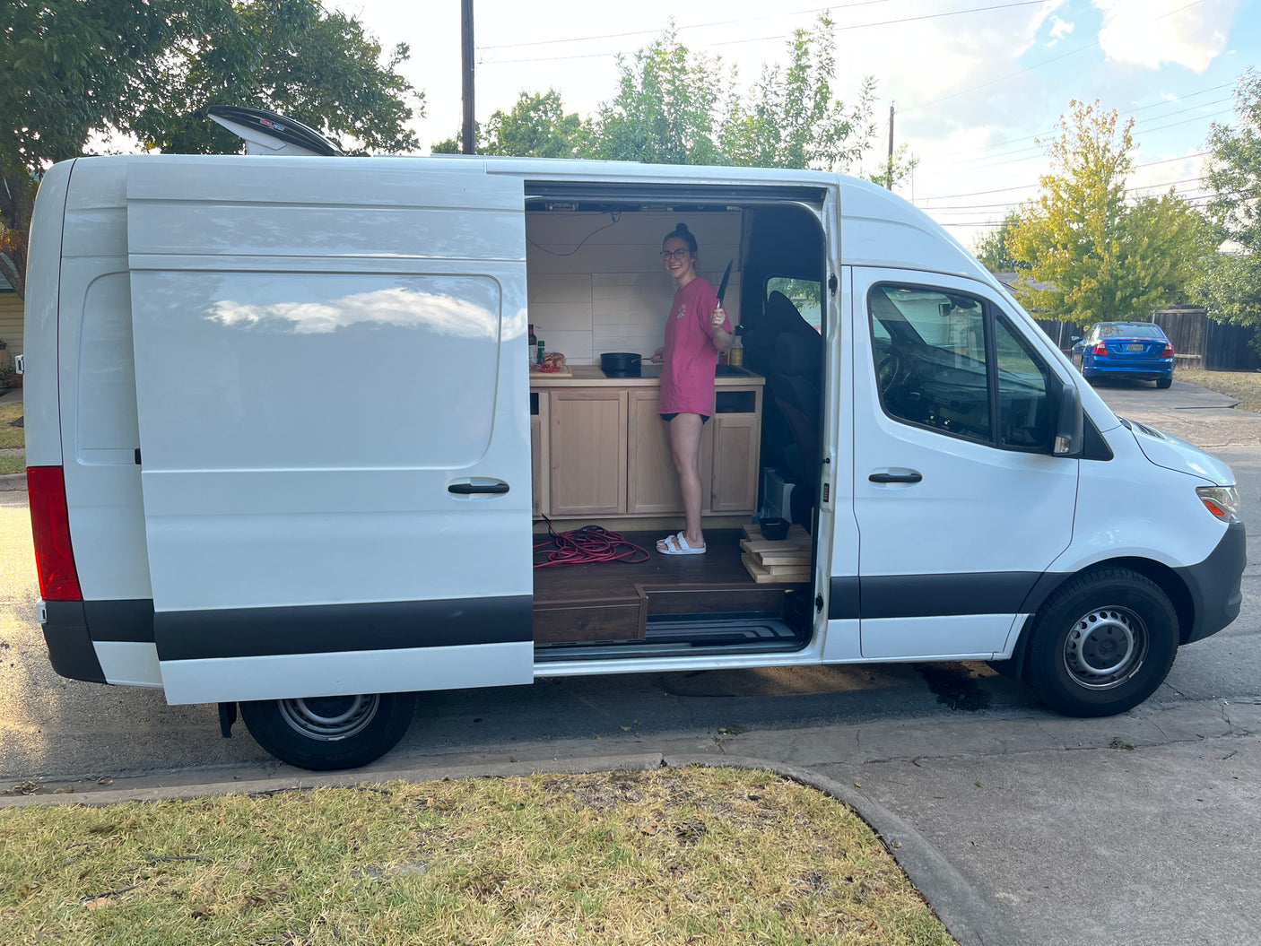 Woman cooking in her RV rental camper van's mobile kitchen, ideal for van life adventures.