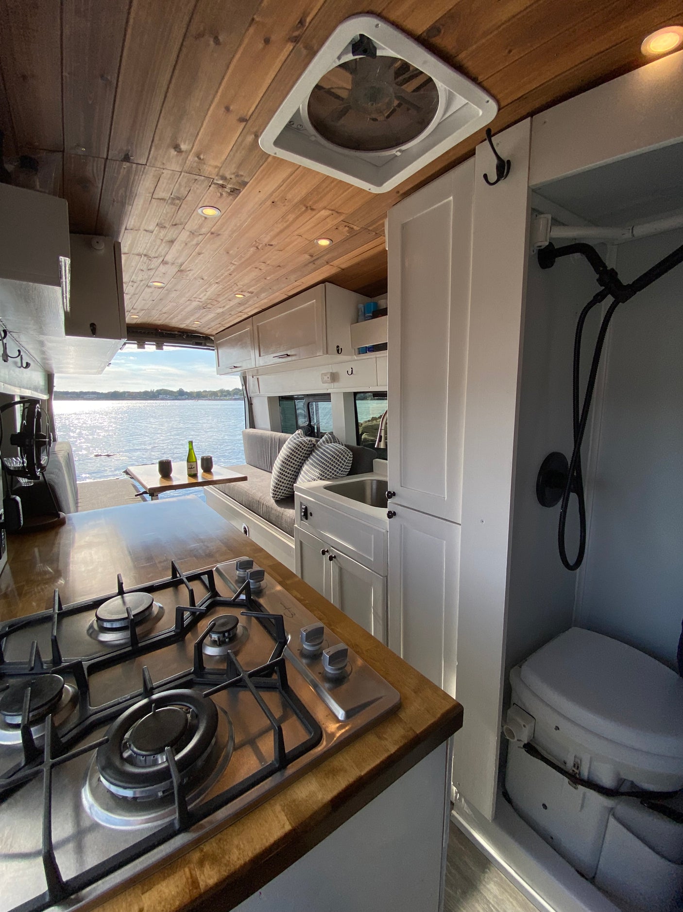 and a stunning sunset view over water. Perfect for travel.|Scenic sunset from a comfy RV rental. A person relaxes on the bed