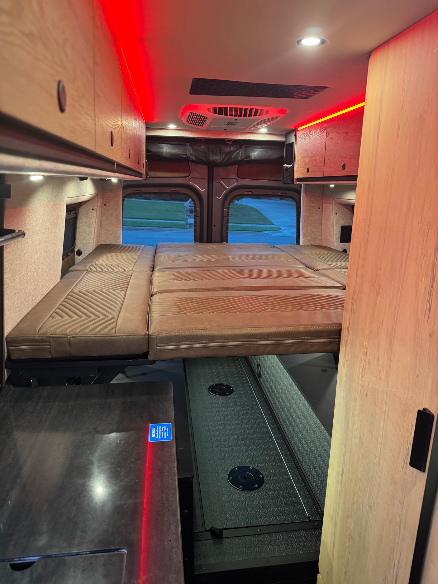 Cozy RV rental interior featuring a plush bed, overhead cabinets, and ambient red lighting for comfortable mobile living.