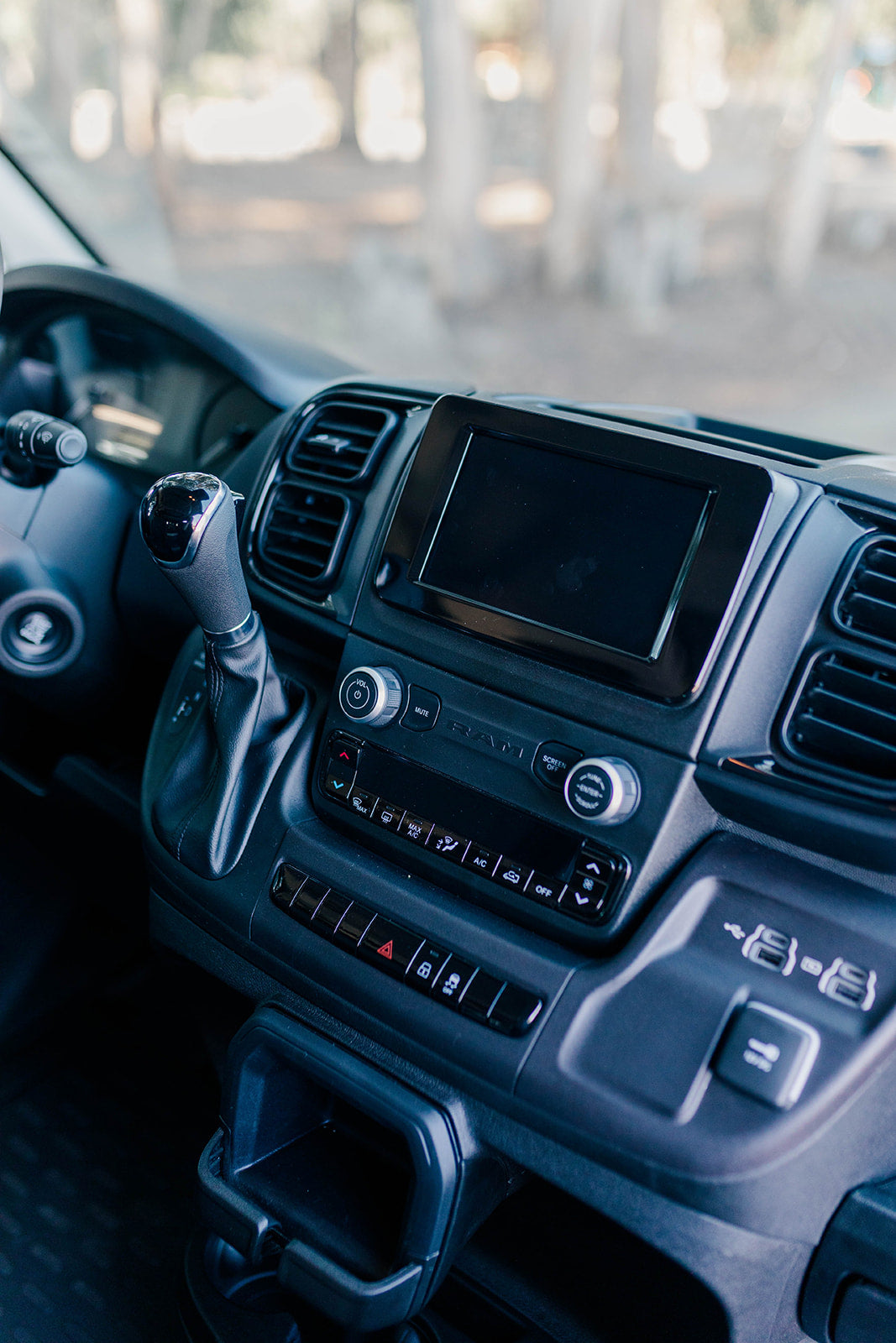 Inside an RV rental: a clear view of the modern dashboard, featuring its screen, gear shifter, and controls for an enjoyable trip.
