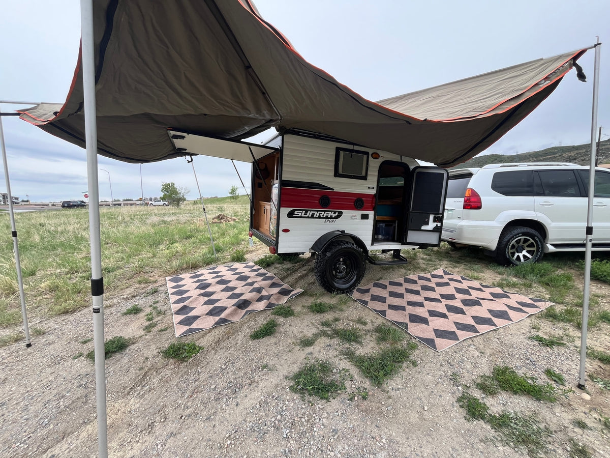 An rv rental teardrop trailer with an awning provides shade for outdoor camping next to a white SUV. — photo 16