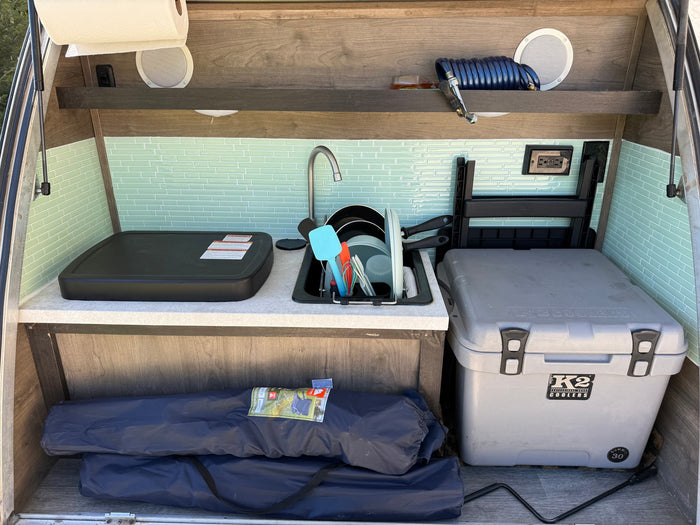 Explore this RV rental's convenient outdoor kitchen, complete with a sink, griddle, and K2 cooler, ready for your camping adventures.