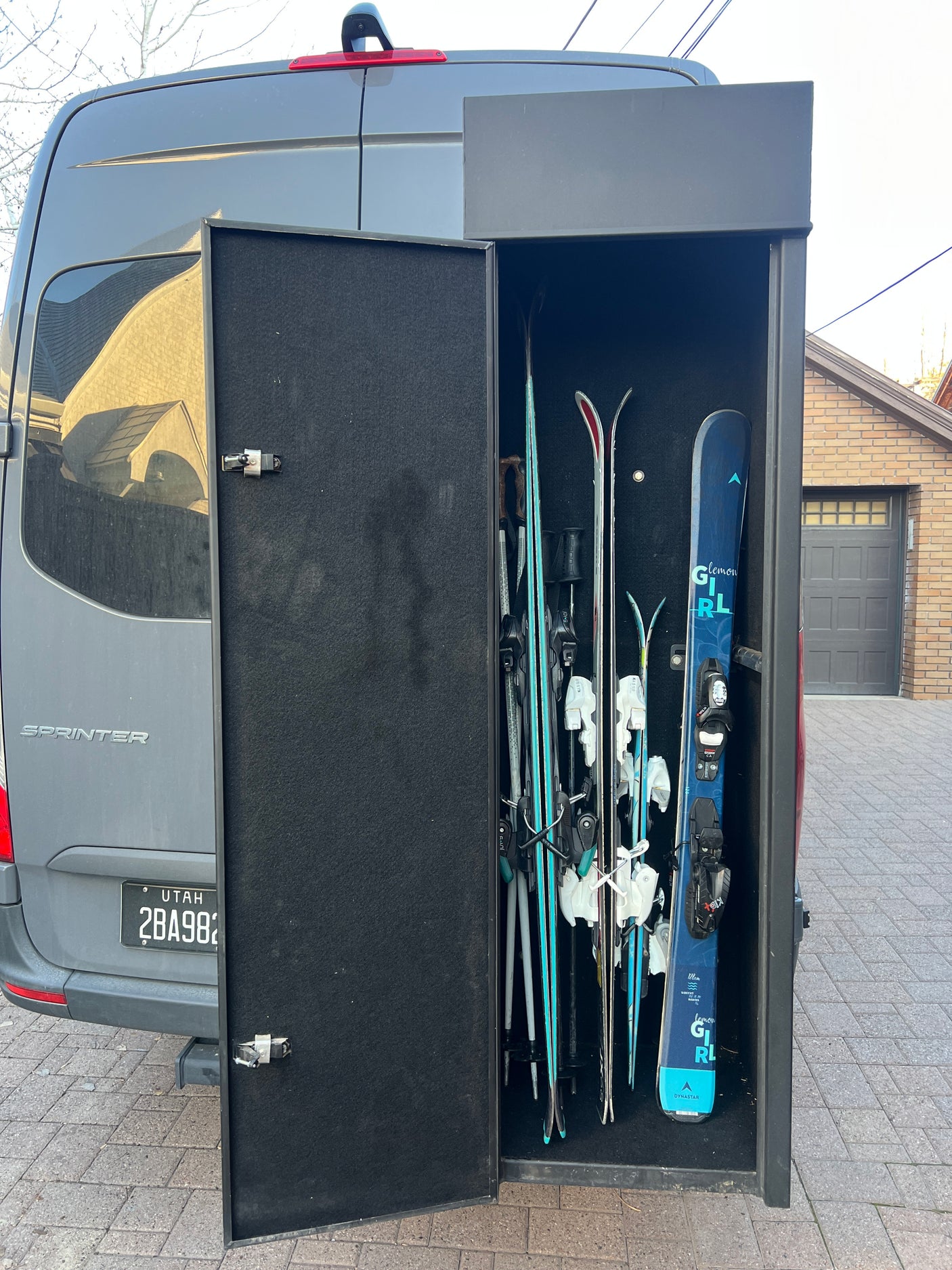 RV rental Sprinter van: custom rear ski storage open, revealing multiple skis and poles for winter sports trips.