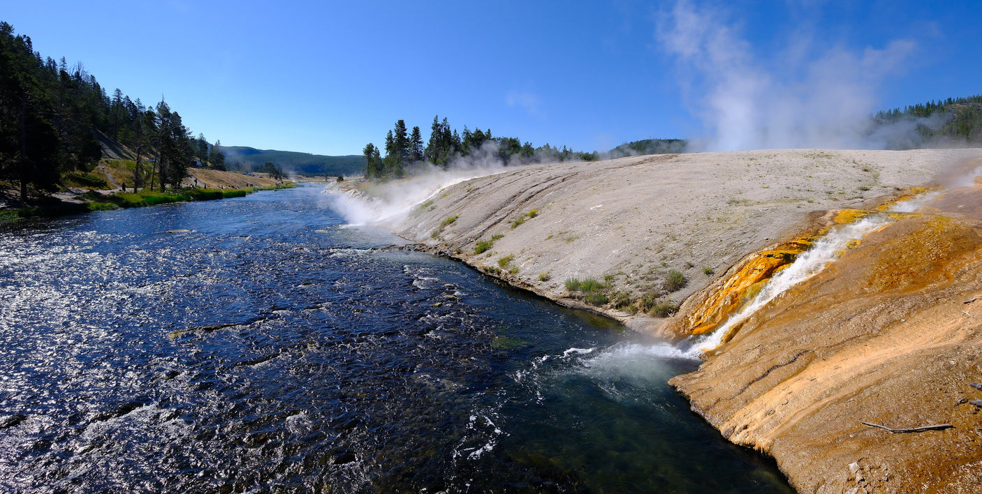Yellowstone's vibrant hot springs cascade into the river, creating steam and color. Discover this beauty with an RV rental.
