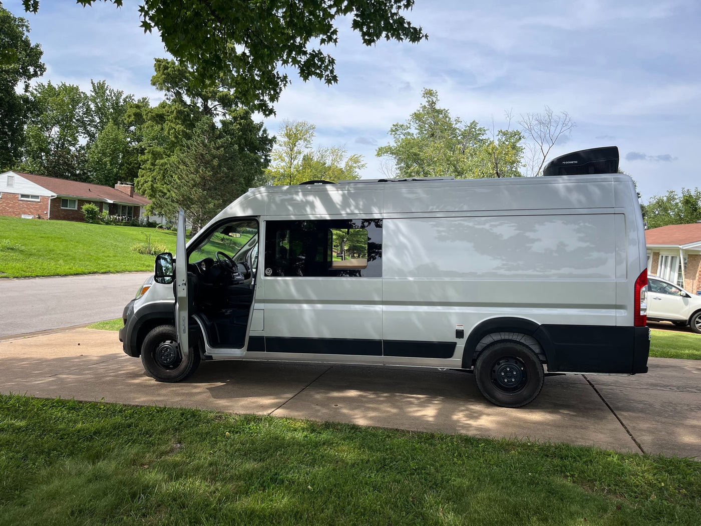 parked on concrete among trees.|This bright white camper van — photo 2
