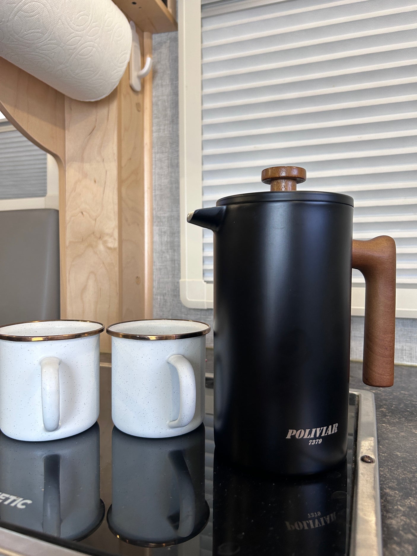 RV rental kitchen essentials: POLIVIAR French press, two enamel mugs, and paper towels, ready for camping.