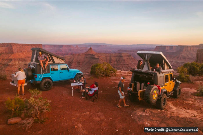 camping with Jeeps & rooftop tents overlooking a desert canyon at sunset.|Blue Jeep with a pop-top rooftop tent