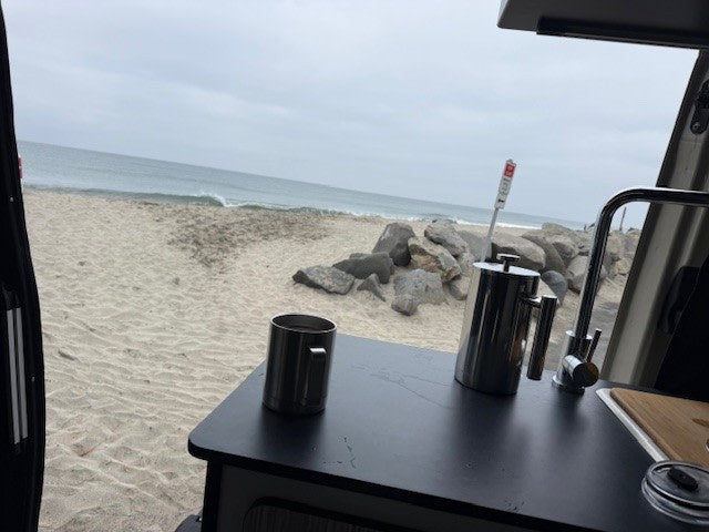 with roof awning & running boards.|A cream rv rental camper van sits on a sandy beach with an extended awning — photo 3