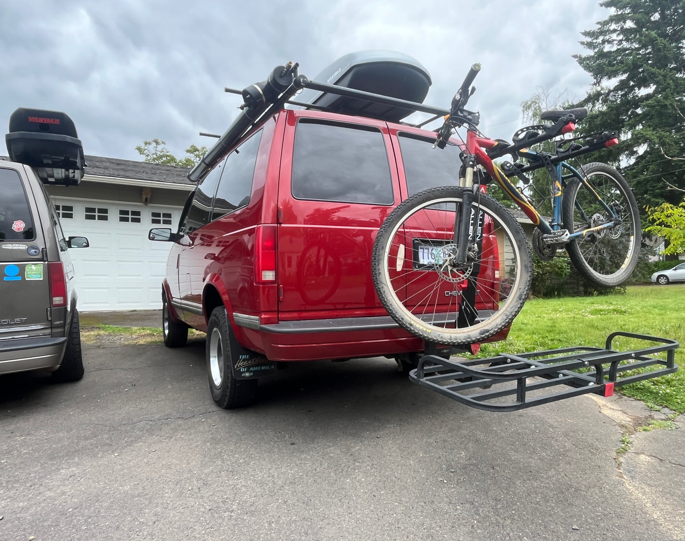Two customized Chevy vans for adventure! The red one sports bikes, roof racks & cargo, perfect for an RV rental trip.