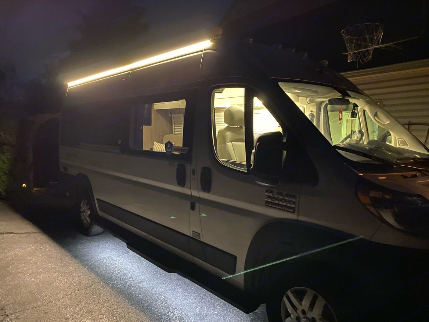 showing comfortable seating and two large windows looking out to a garage and nature.|RV rental tech zone: Open cabinet with Wi-Fi guard