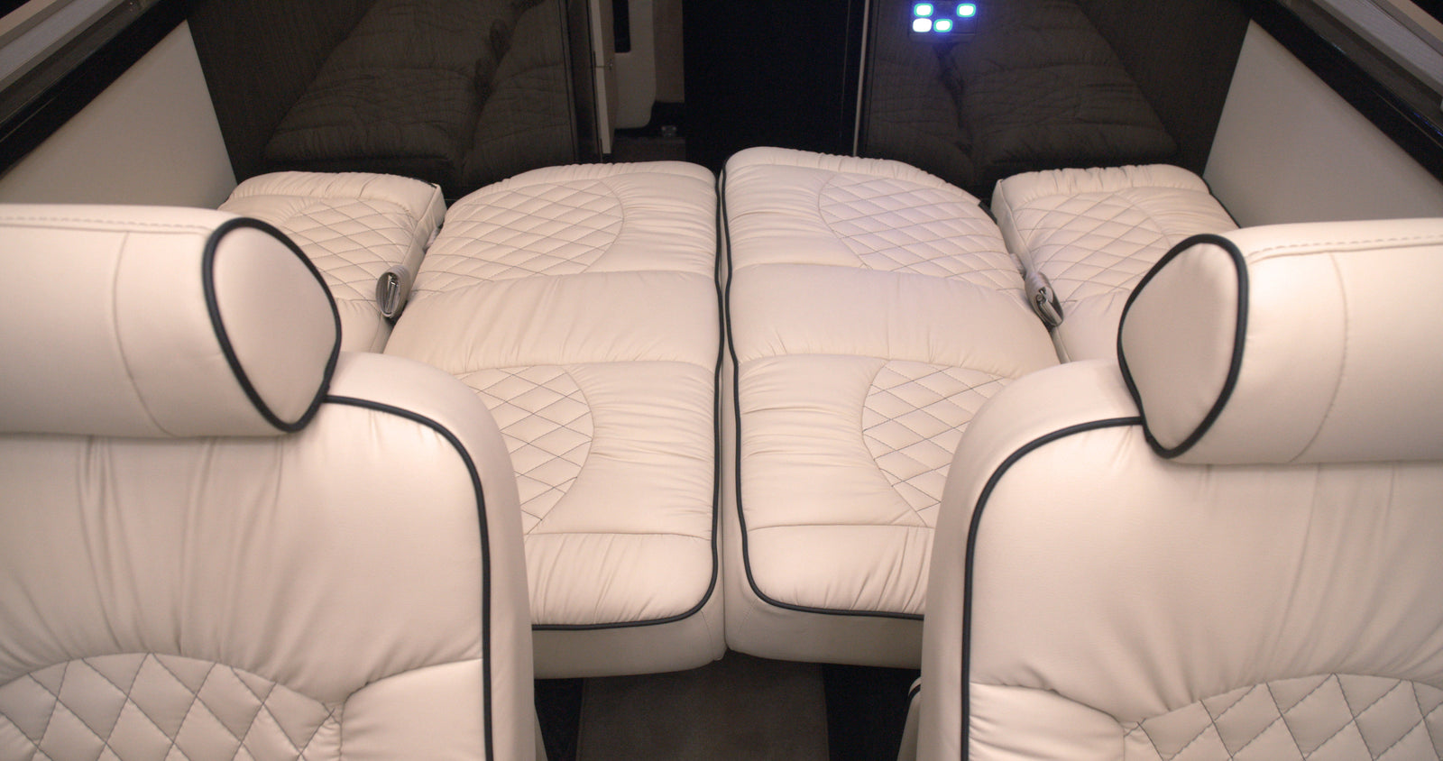 quilted leather captain's chairs for ultimate travel comfort.|Luxury rv rental interior showcasing illuminated ceiling panels