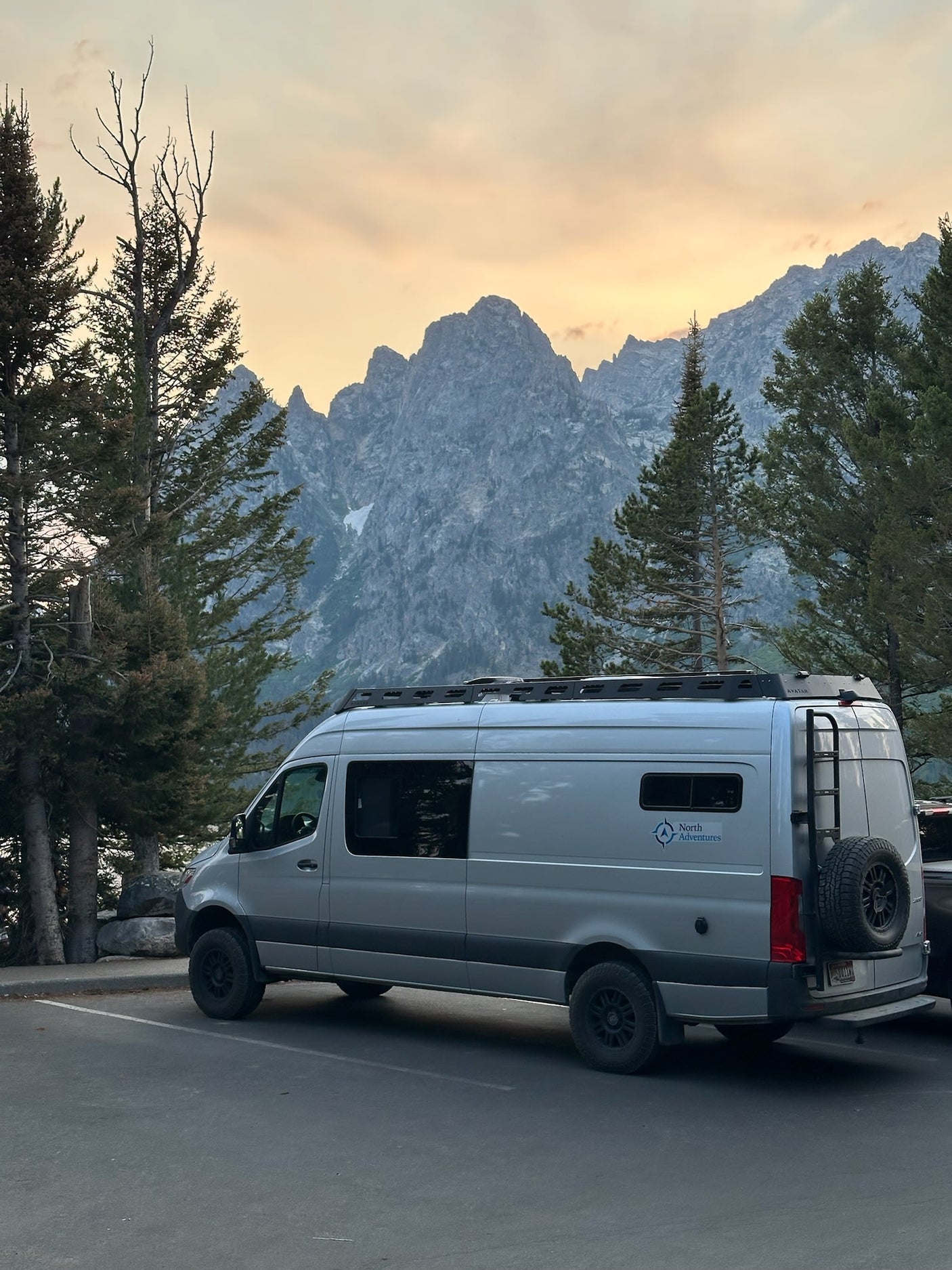 and ambient lighting.|Inside a custom RV rental van: a comfy bed with blue bedding