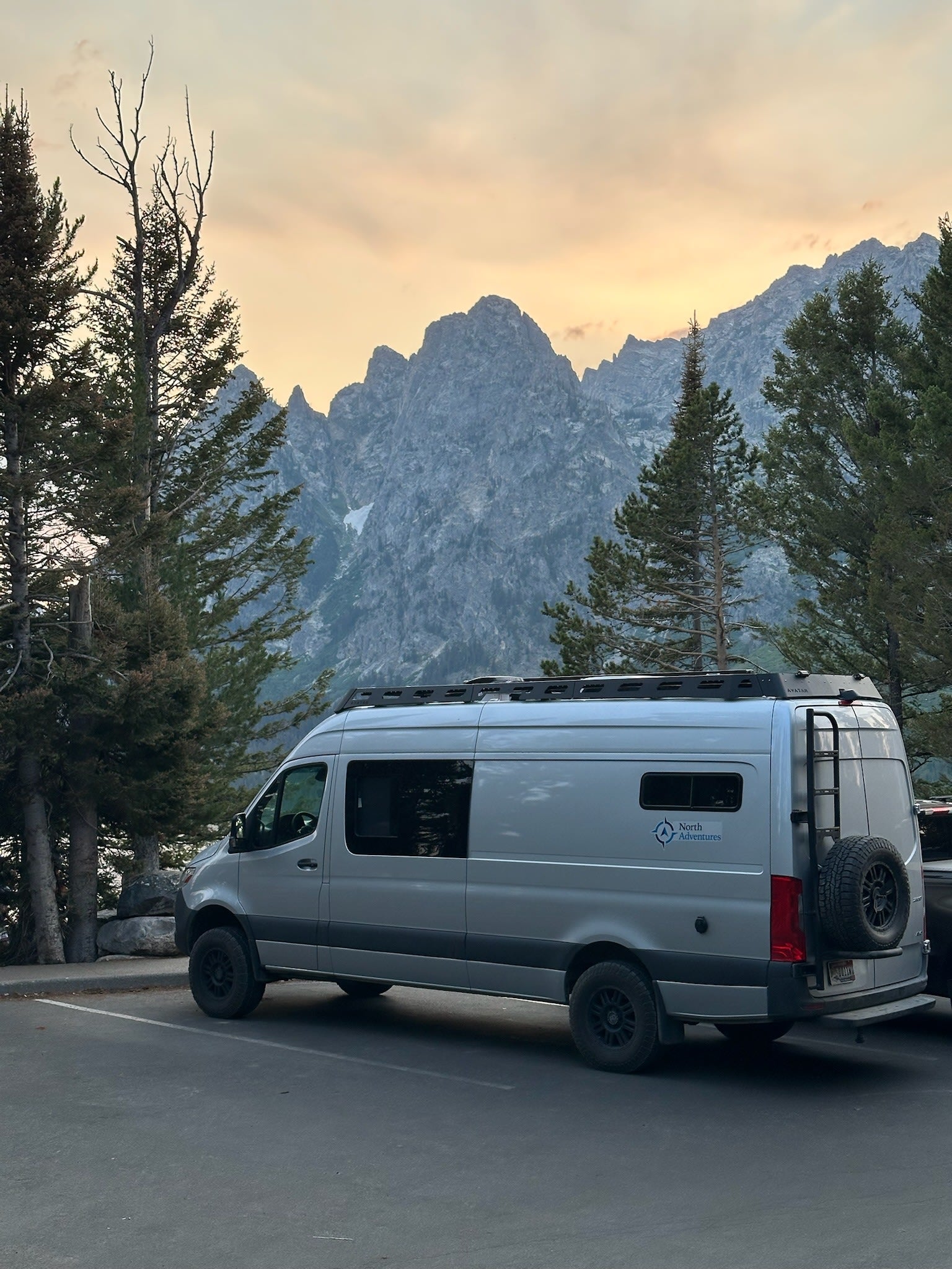 and ambient lighting.|Inside a custom RV rental van: a comfy bed with blue bedding