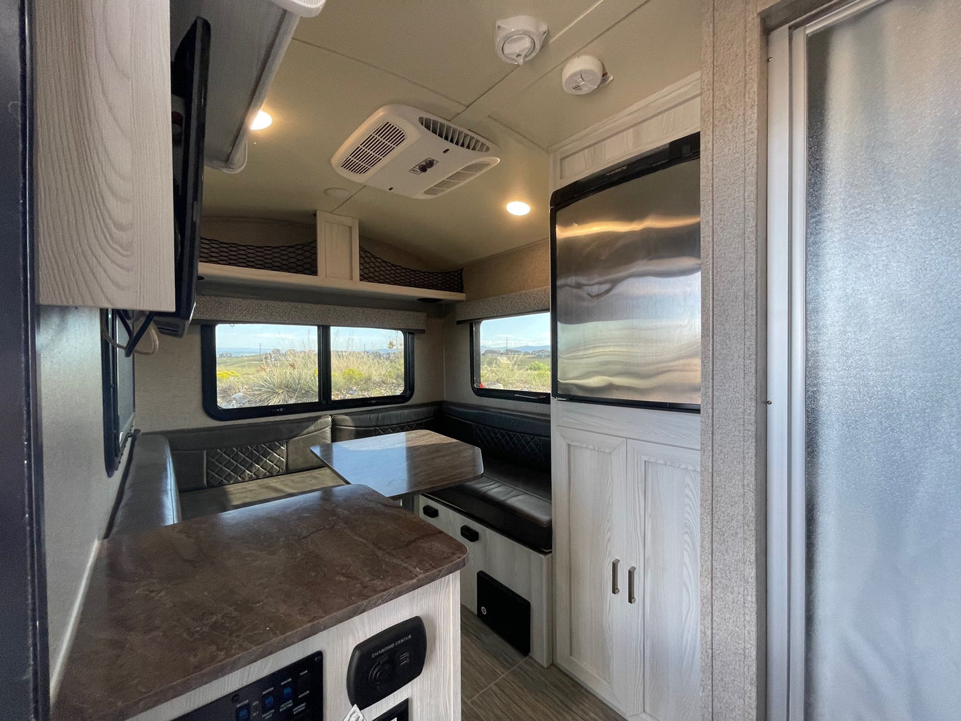 is nestled in a forest campsite by a rocky stream.|Geo Pro RV rental travel trailer with awning extended — photo 2