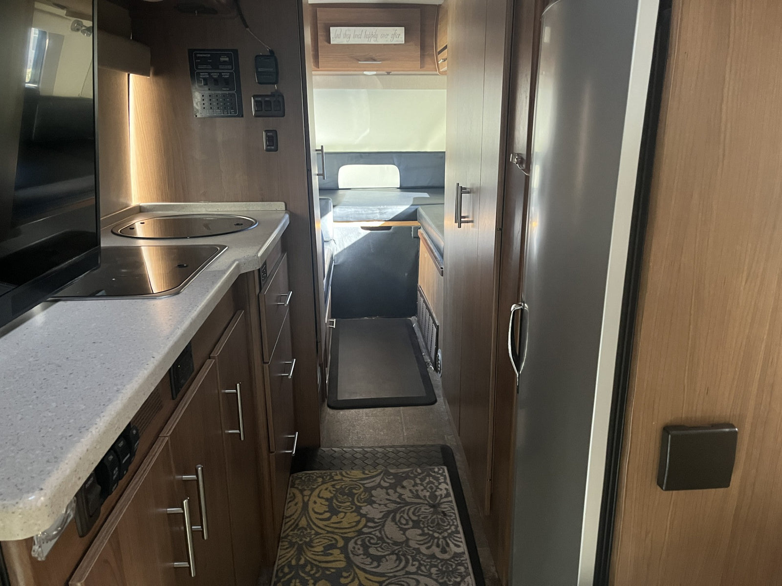 RV rental interior: A compact kitchen with a control panel leads to a hallway and rear living/sleeping area.