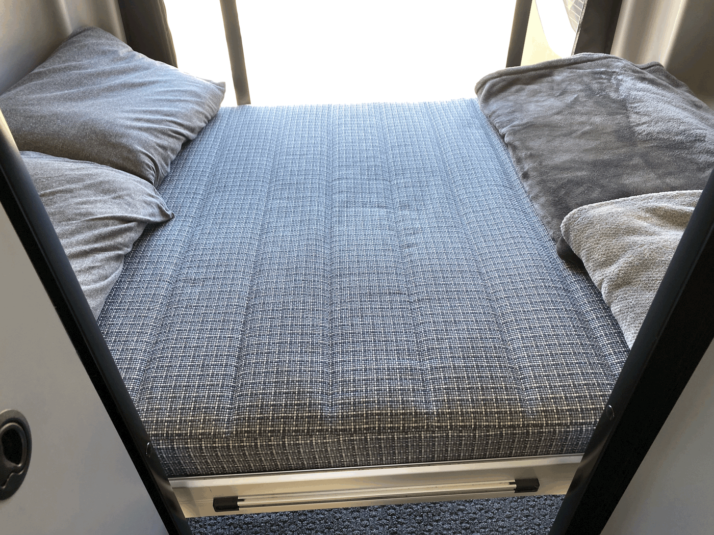 Cozy RV rental sleeping area featuring a patterned mattress, soft pillows, and blankets for comfortable travel. — photo 6
