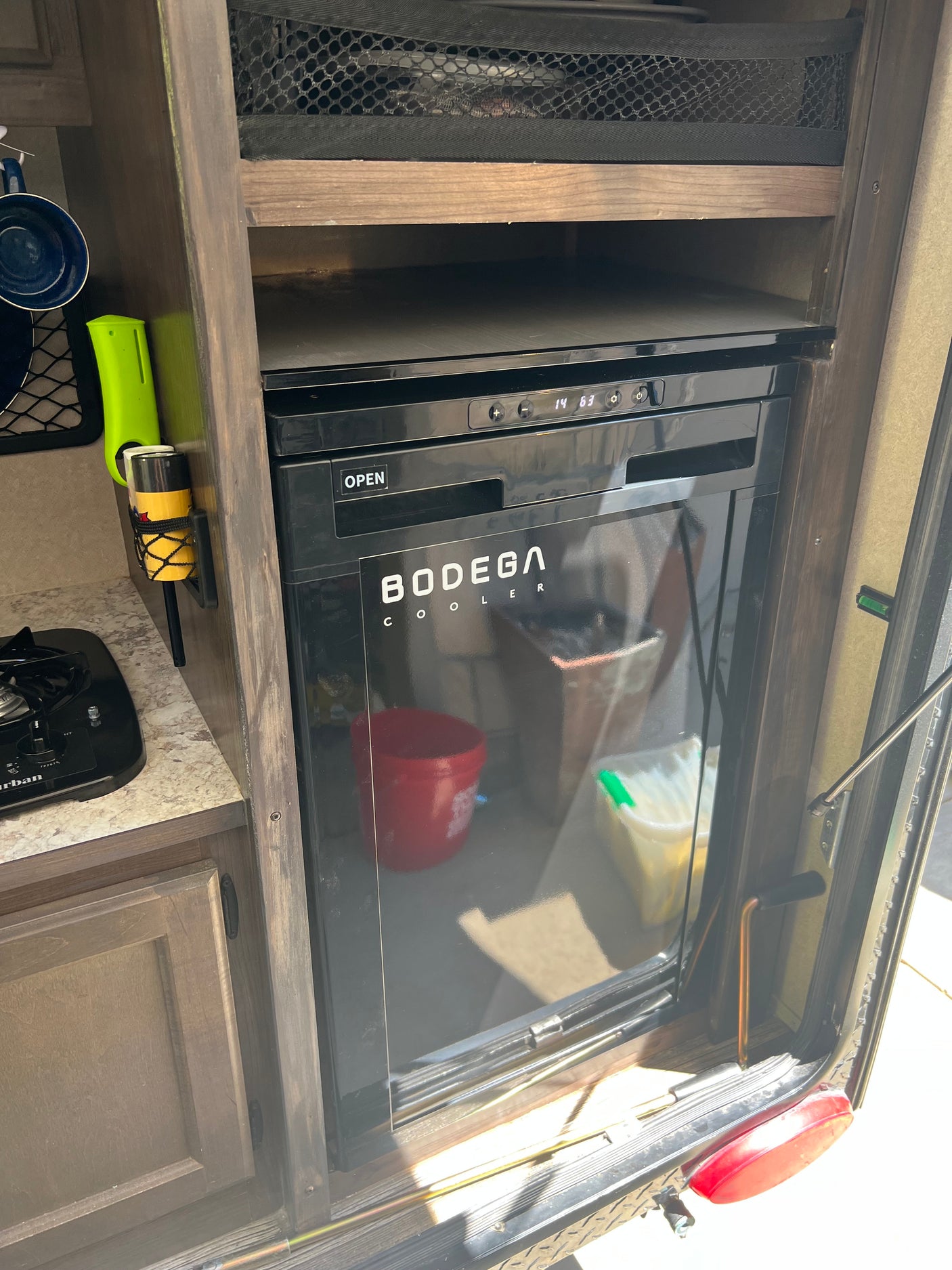 Compact RV rental kitchenette featuring a built-in Bodega cooler, ideal for efficient travel and convenient storage.