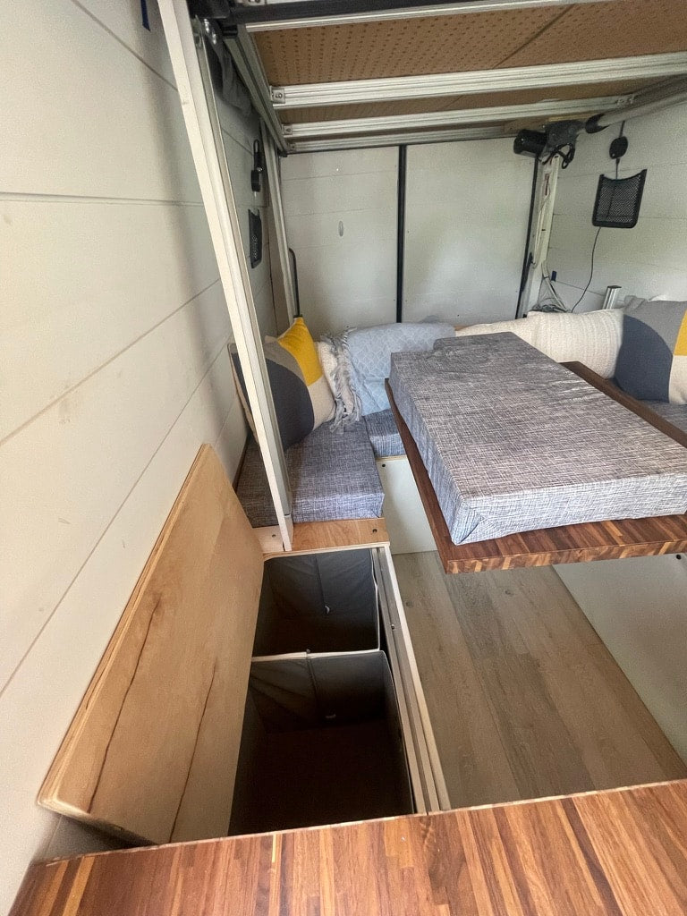 and a well-equipped kitchenette.|Cozy RV rental interior shows a large bed with striped pillows