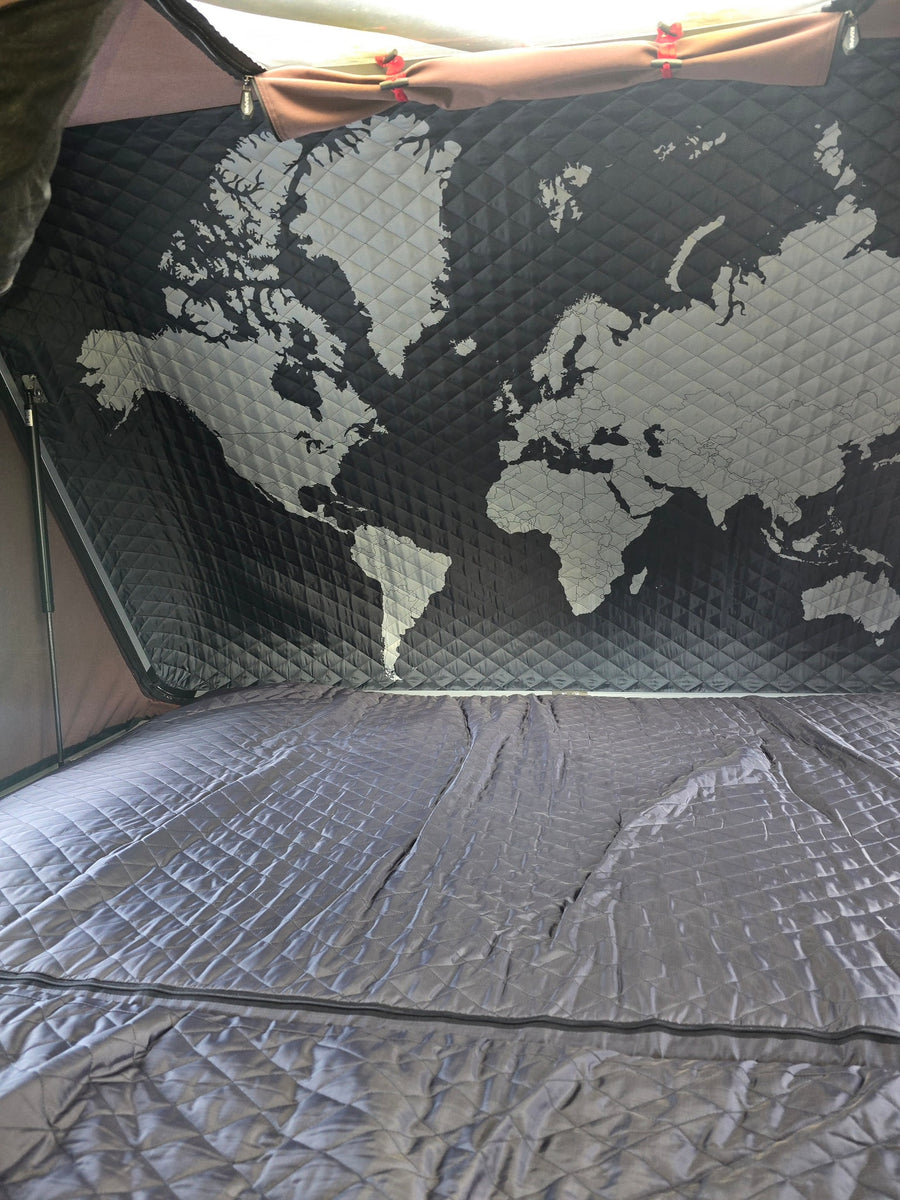 Cozy RV rental interior: a quilted world map adorns the ceiling above a matching, comfortable bed.