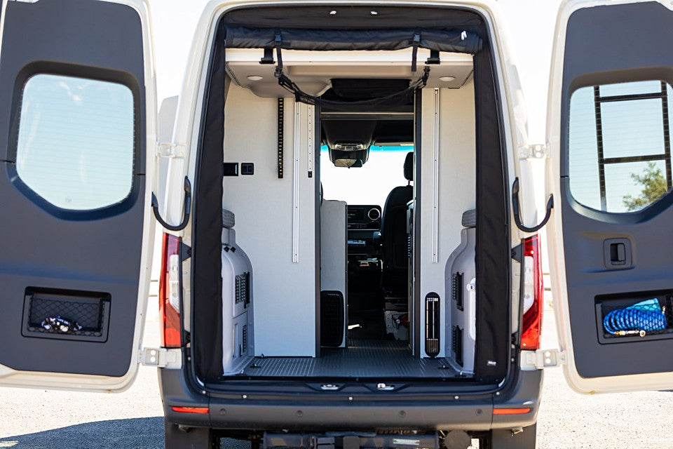 RV rental camper van's organized rear interior with open doors revealing storage pockets and a clear path leading to the front cabin.