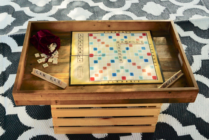 A Scrabble game board with 'HAPPILY,' 'HITCHED' words, plus tiles on racks (C,A,M,E,R,S & D,R,E,A,M). Great for your rv rental!