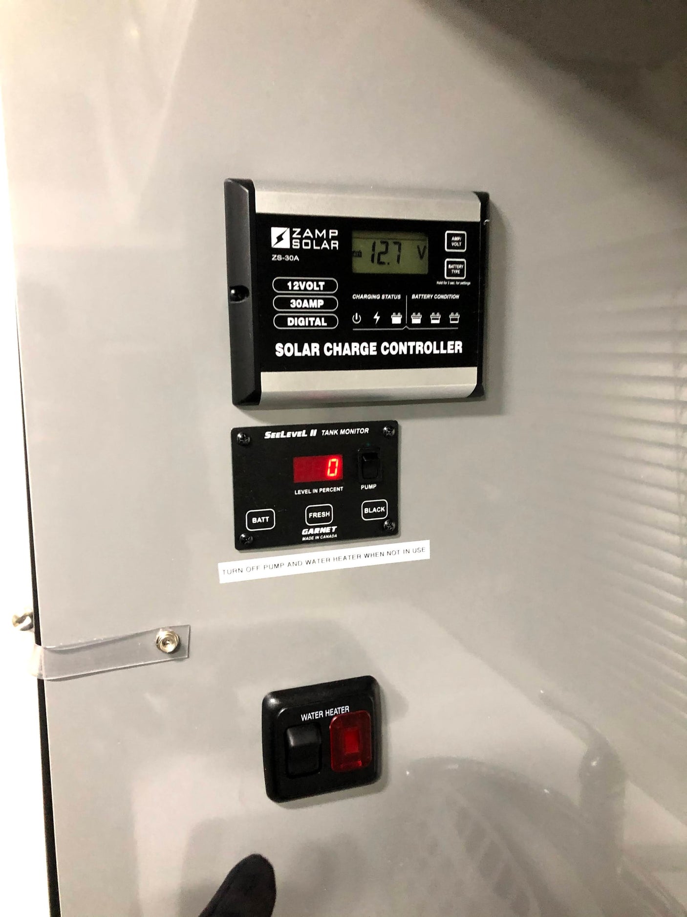 RV rental control panel showing solar charge (12.7V), tank monitor (0% shown), and water heater switch for system management.