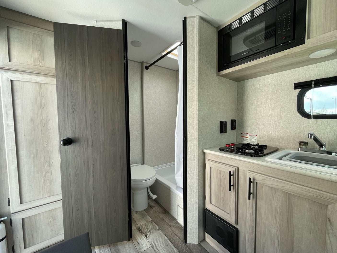 plus a dining area with bench seating.|RV rental interior: a compact kitchenette with stove/sink