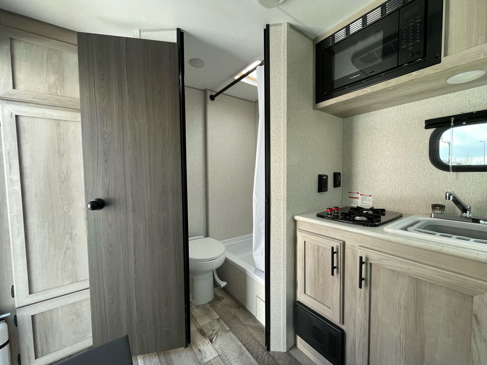 plus a dining area with bench seating.|RV rental interior: a compact kitchenette with stove/sink