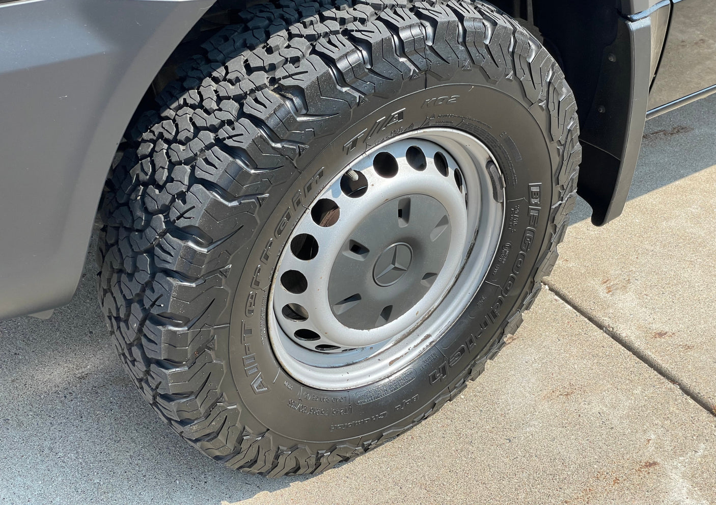 A close-up view of a rugged BFGoodrich all-terrain tire and Mercedes wheel on an RV rental van, ready for the road.
