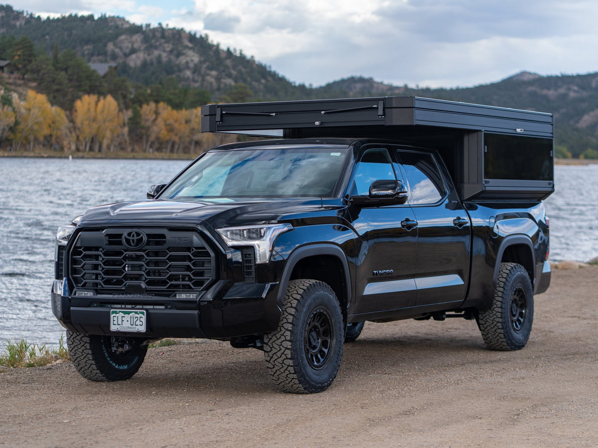 Experience outdoor freedom! This black Toyota Tundra with a truck bed camper is perfect for your next rv rental adventure.|Black Toyota Tundra with an overlanding camper — photo 1