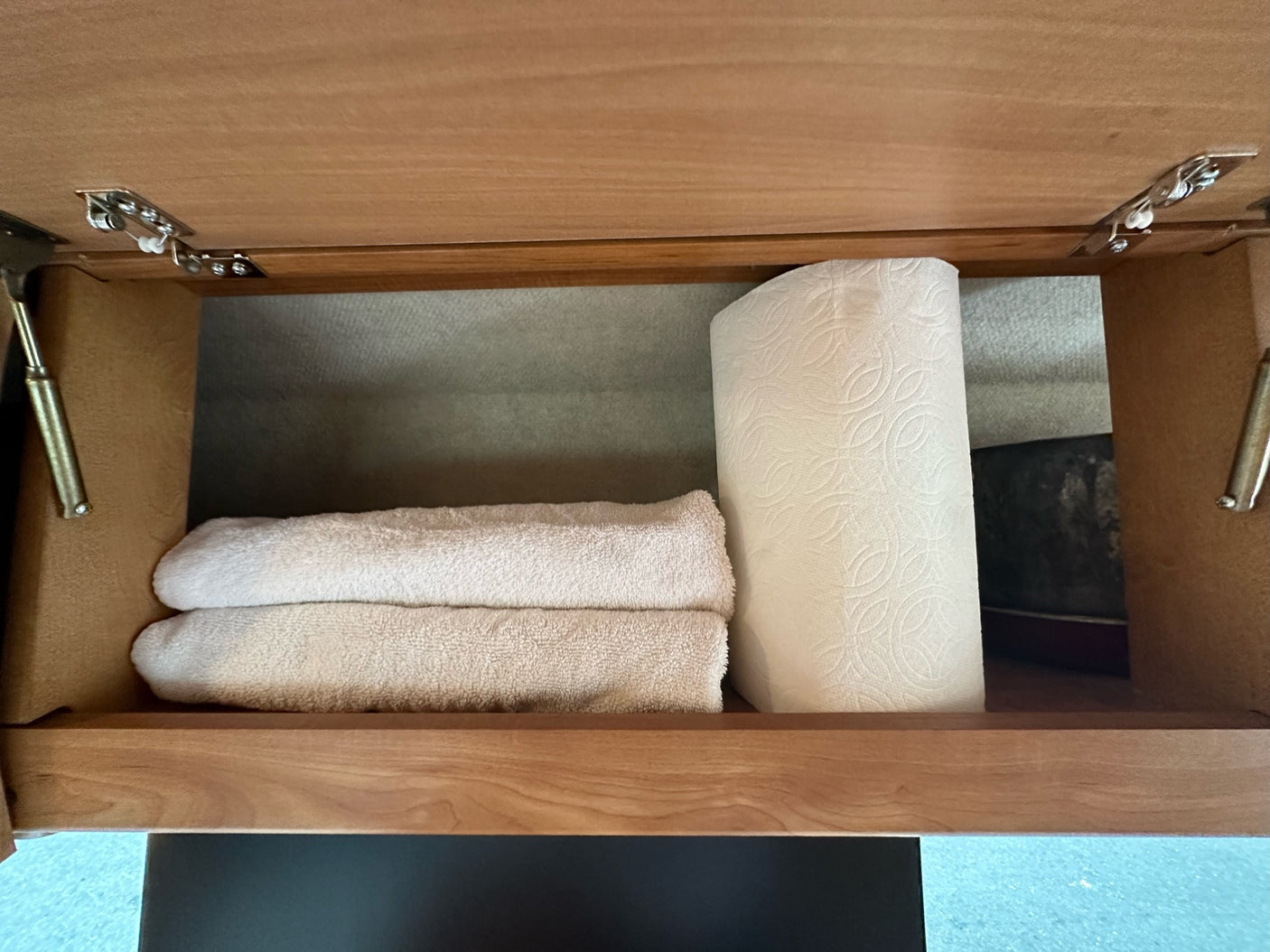 Clean towels & paper towels neatly stored in an RV rental's overhead cabinet, ready for your trip.