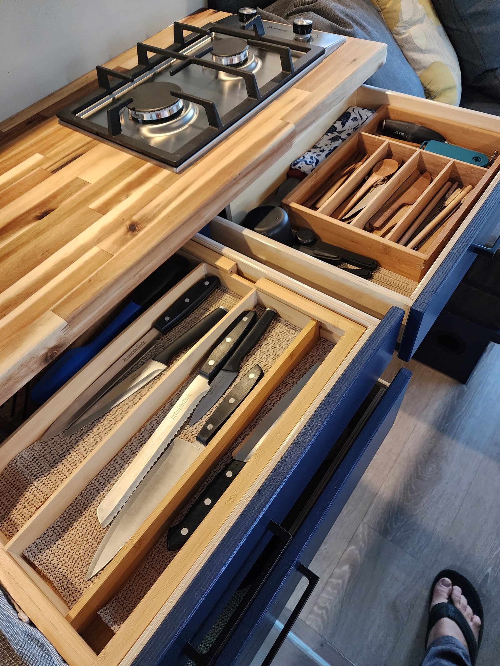 RV rental kitchen features a 2-burner stove, plus neatly organized wooden utensils & knives in pull-out drawers.