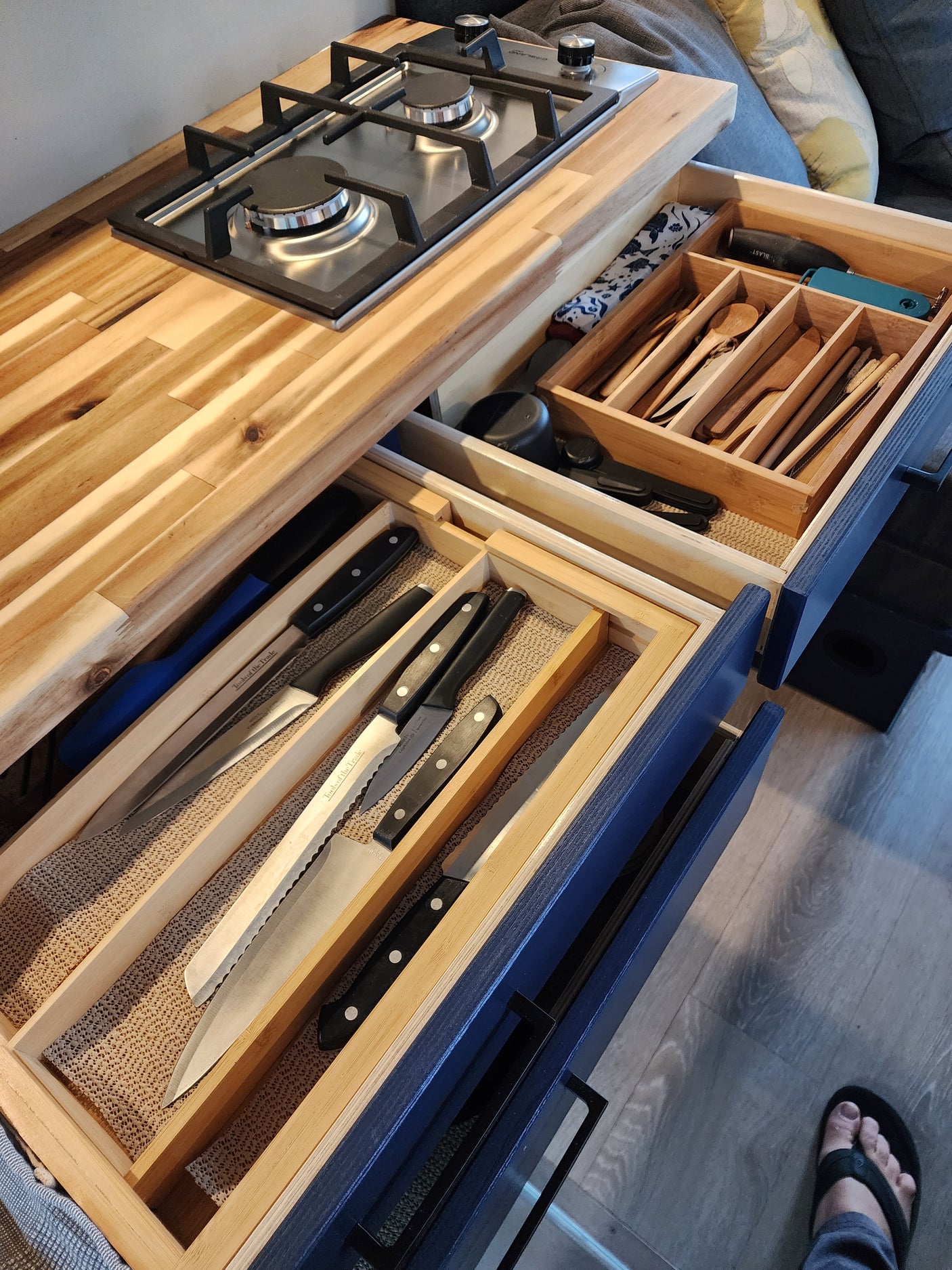 RV rental kitchen features a 2-burner stove, plus neatly organized wooden utensils & knives in pull-out drawers.