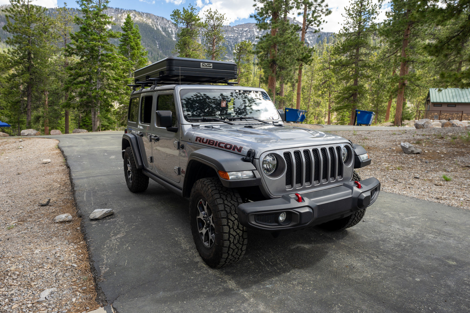 Gray Jeep Wrangler Rubicon with rooftop tent, ideal for your next RV rental adventure amidst mountains.
