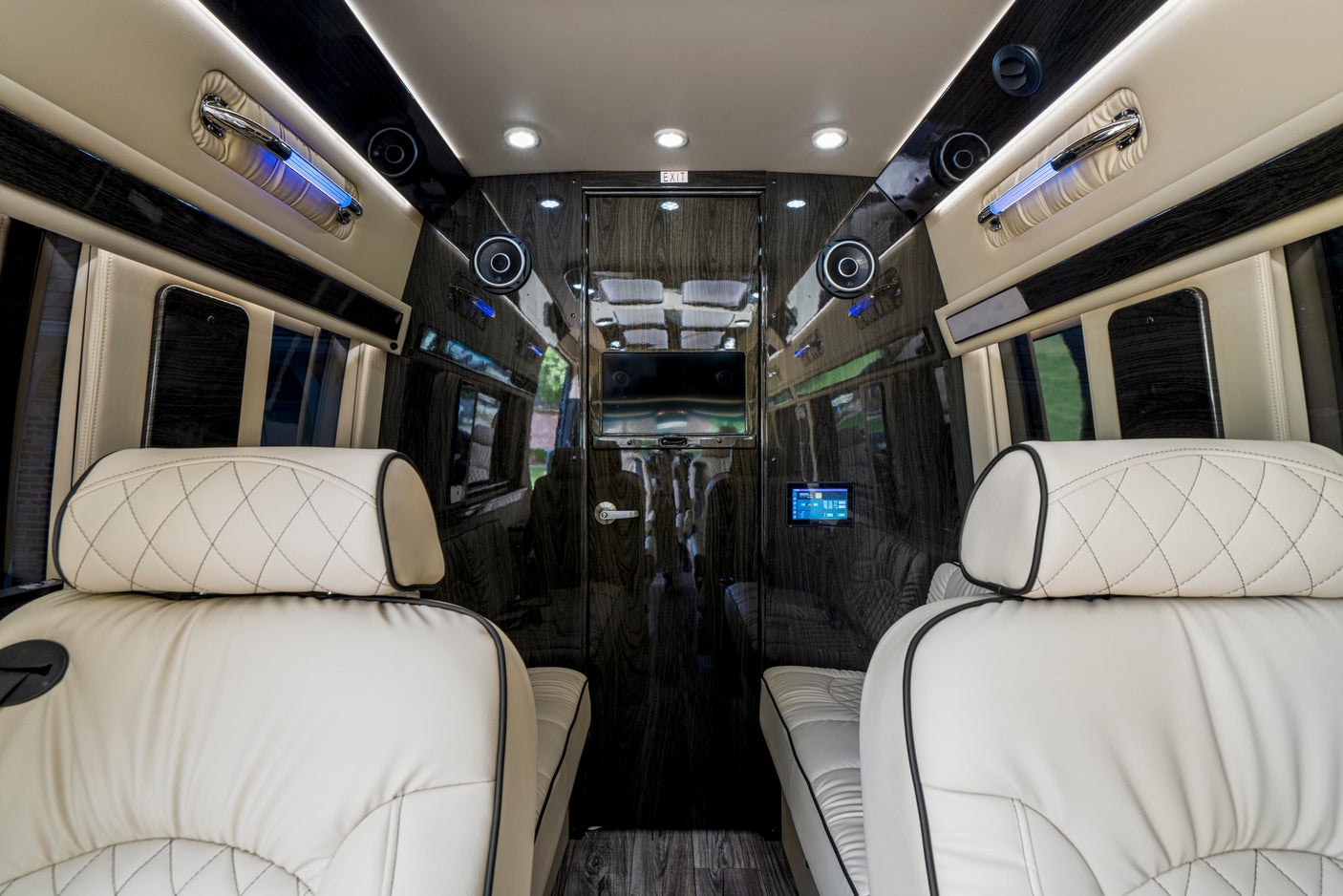 Step inside this luxury RV rental featuring cream leather seats, dark wood paneling, ambient lighting, and entertainment.