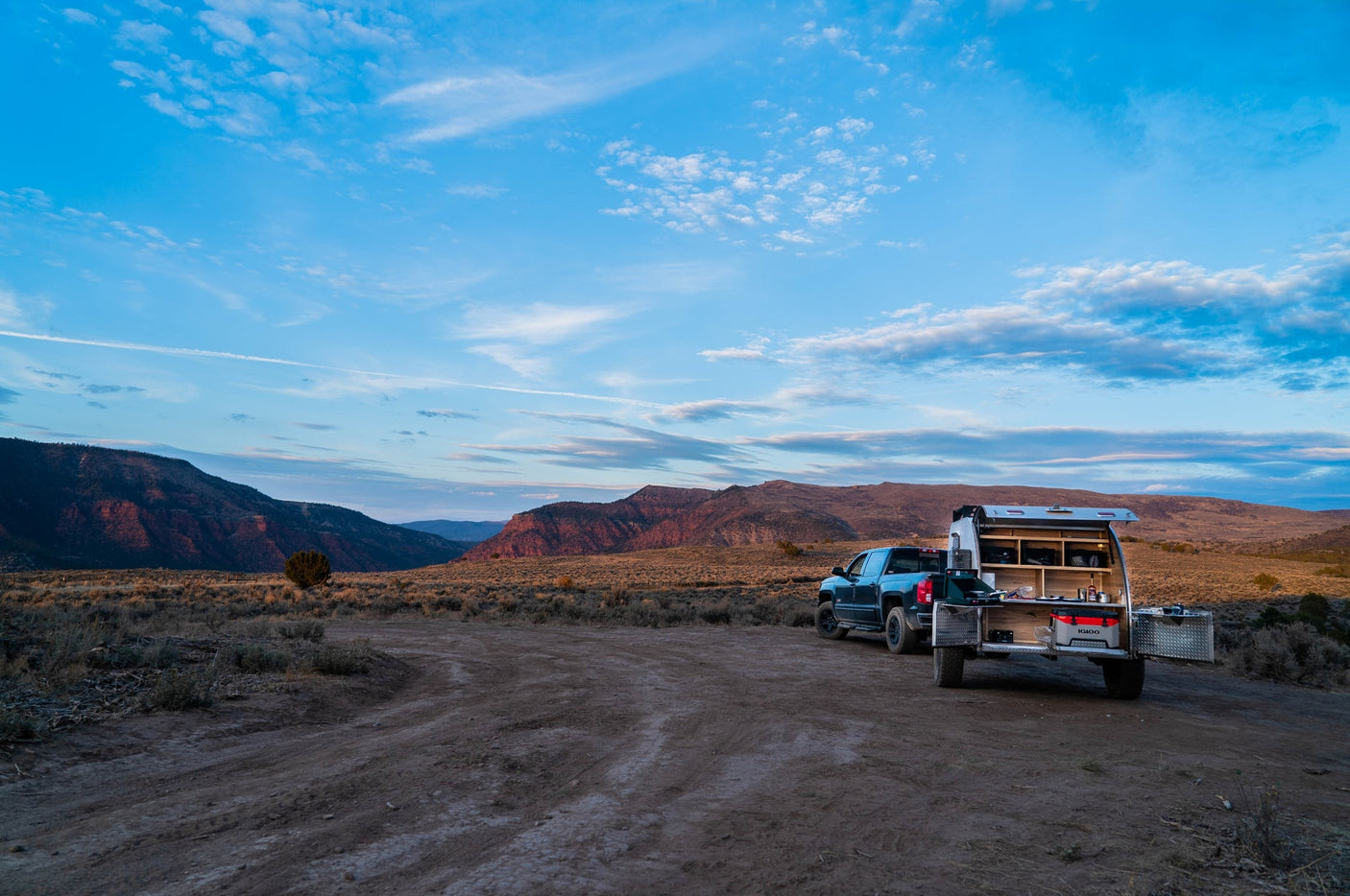 RV rental truck with an open camper kitchen set up in a vast desert landscape at sunset/sunrise. Remote camping adventure awaits!