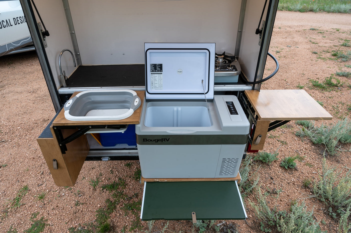 This RV rental's outdoor kitchen boasts a portable fridge, folding sink, stove, and convenient pull-out work surfaces.